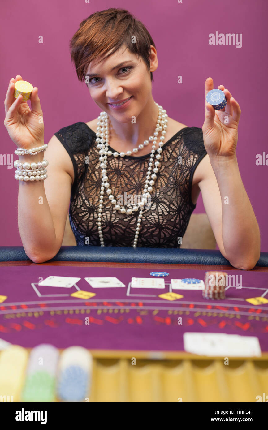 Woman sitting in a casino at table with chips in her hand Stock Photo