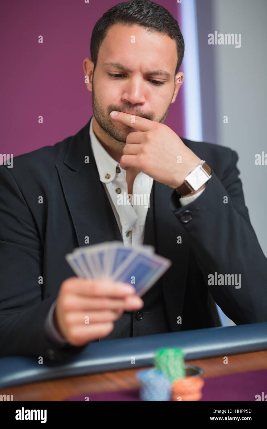 Man looking at his cards thinking while sitting at casino Stock Photo