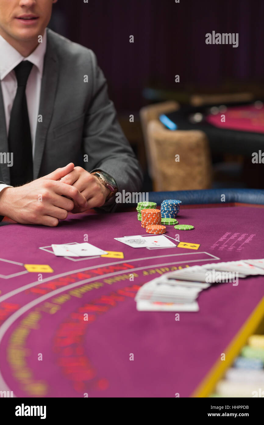 Man sitting at poker tabe with cards and chips in casino Stock Photo