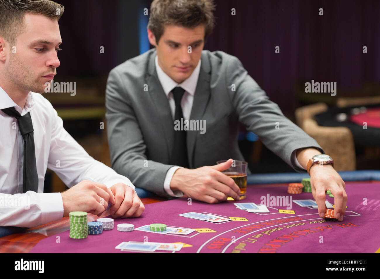 Men placing bets at poker game in casino Stock Photo