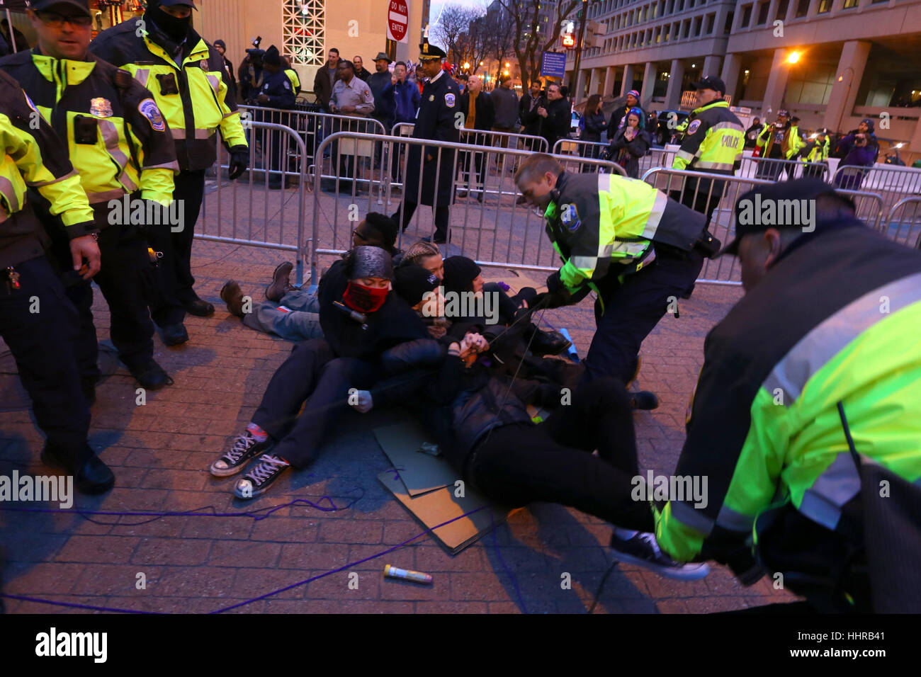 Washington DC, USA. January 20, 2017. Police tear a woman away from a larger group of demonstrators blockading a security checkpoint into the inauguration parade. Demonstrators used direct action techniques--U locks locked around their necks--to stymie efforts by police to remove them from the location. The protesters, organized under The Future is Feminist, was one of several groups disrupting access to the Inaugural Parade. Stock Photo