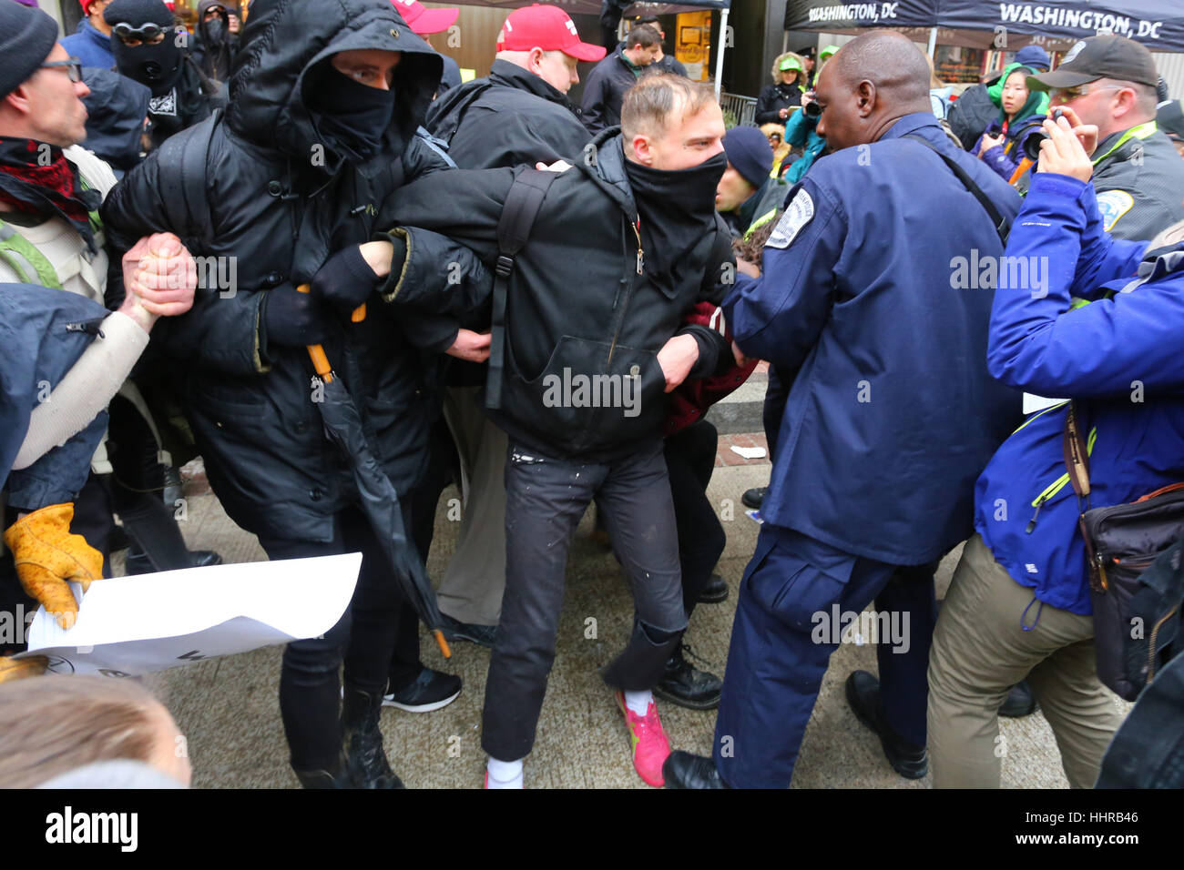 Washington DC, USA. January 20, 2017. Black-clad protesters use direct action techniques--of linking arms--to resist a police attempt to separate them at a security checkpoint blockade into the Inaugural Parade. Stock Photo