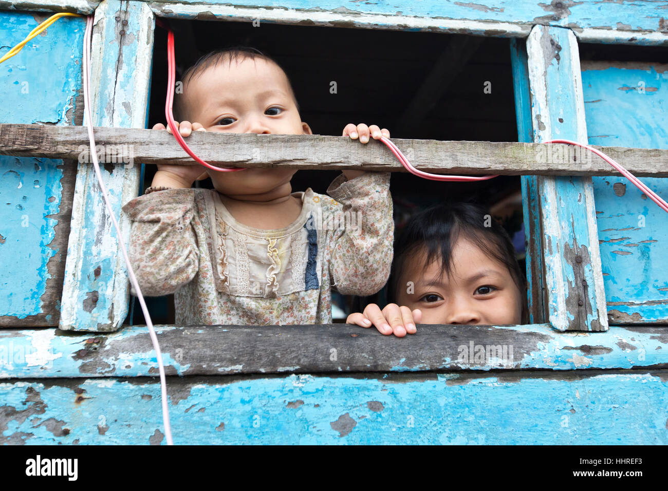 Two young children peeking from porthole, floating market. Stock Photo