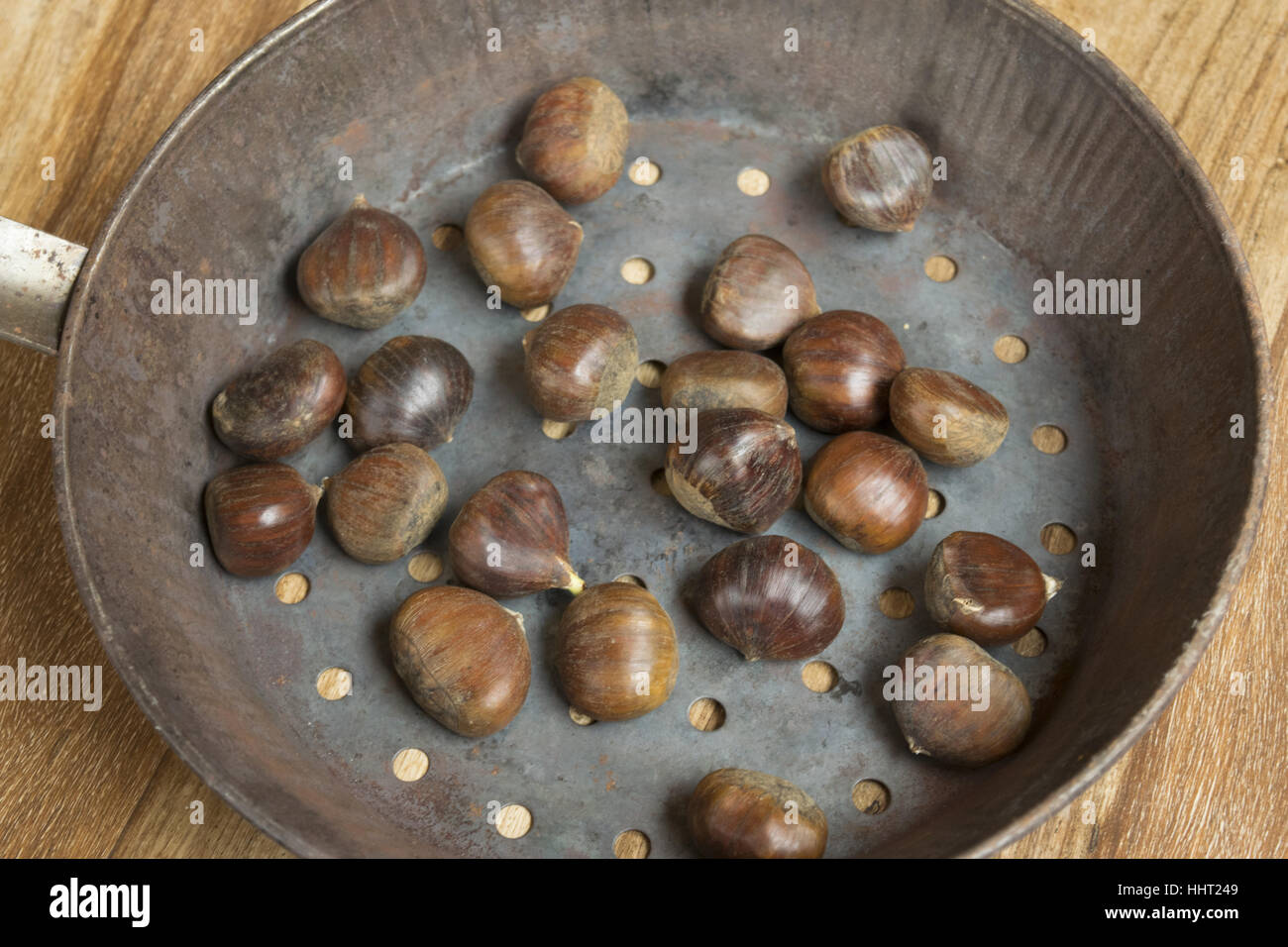 Premium Photo  Roasted chestnuts in a chestnut pan skillet with holes on a  aged brown wooden table