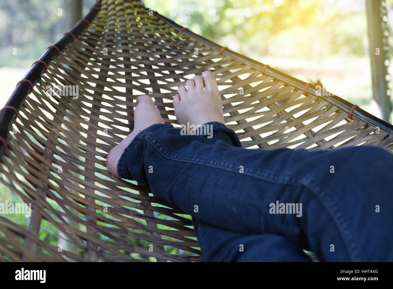 feet of woman wearing jeans resting, relaxing, sleeping on rattan