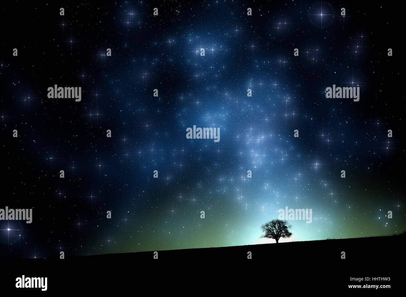 Tree on hill in night landscape. Starry sky and milky way, surreal scenery Stock Photo