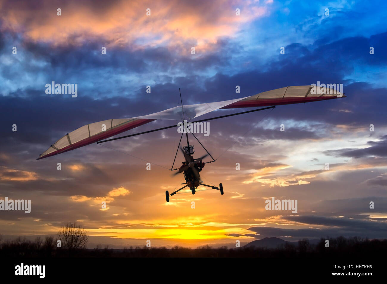 Motorized hang glider flying in the sunset Stock Photo