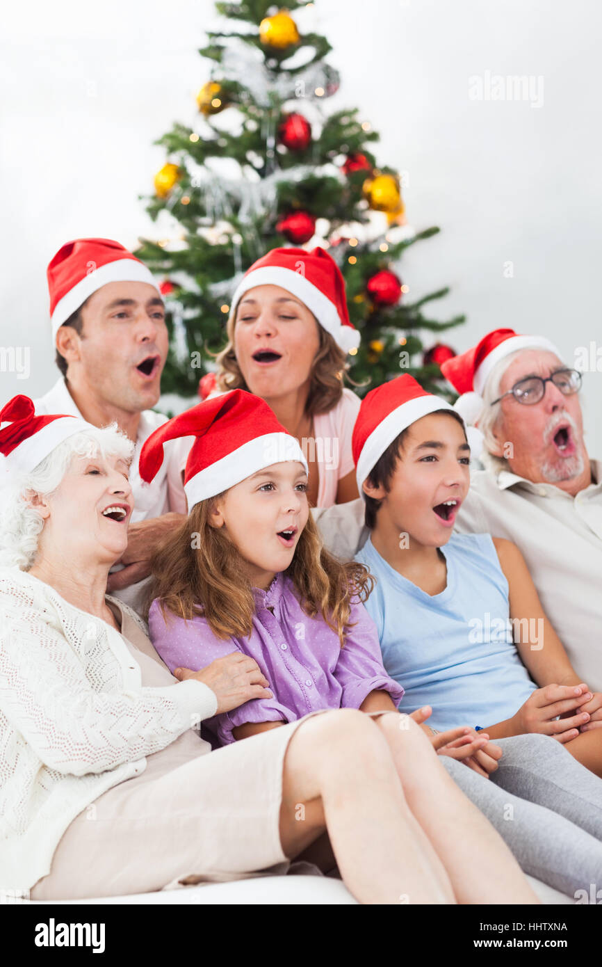 Extended family singing christmas carols together on couch Stock Photo