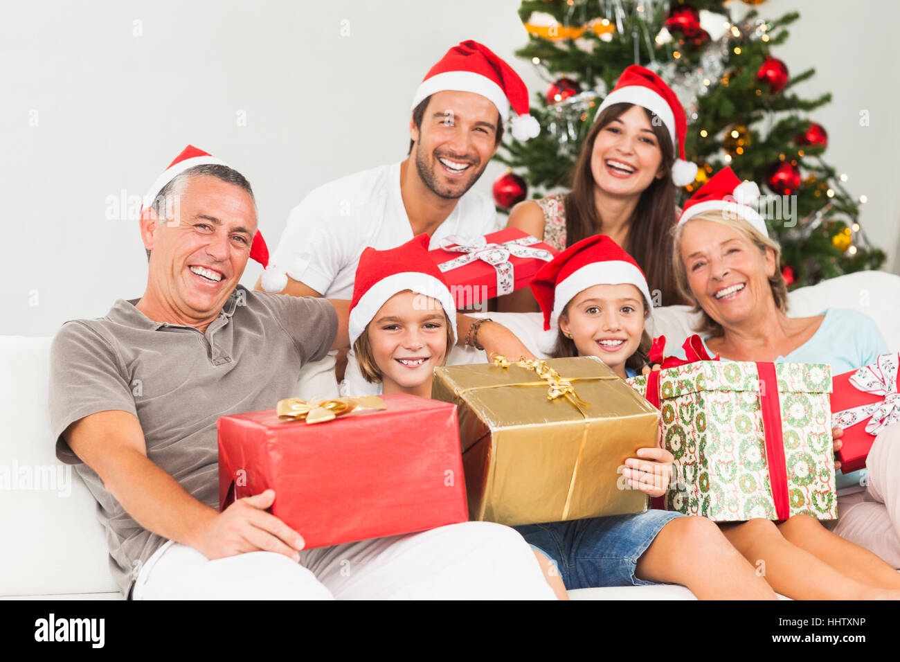 Happy family at christmas holding gifts on the couch Stock Photo