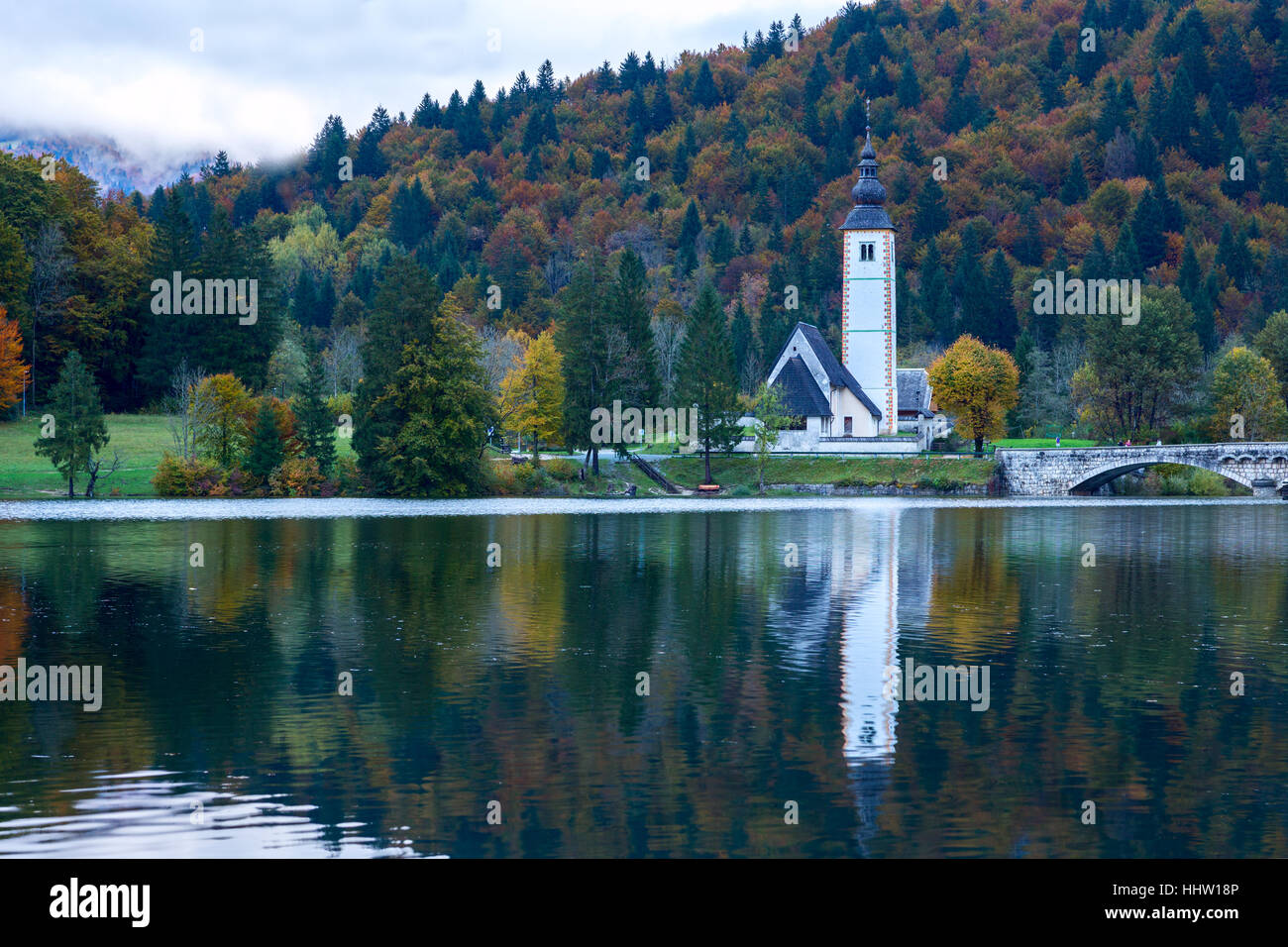 Church tower and stone bridge at Lake Bohinj in alpine village Ribicev Laz, Slovenia Stock Photo