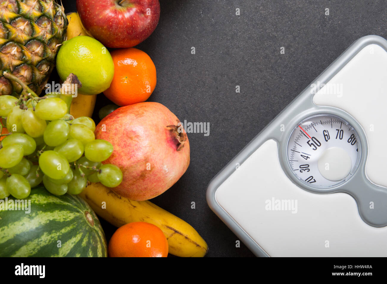 Stack of fruits and white weight scale on stone countertop . Concept of diet and healthy lifestyle Stock Photo