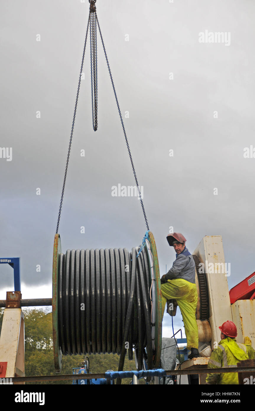 Workers load cable onto a barge in Truro, Cornwall Stock Photo