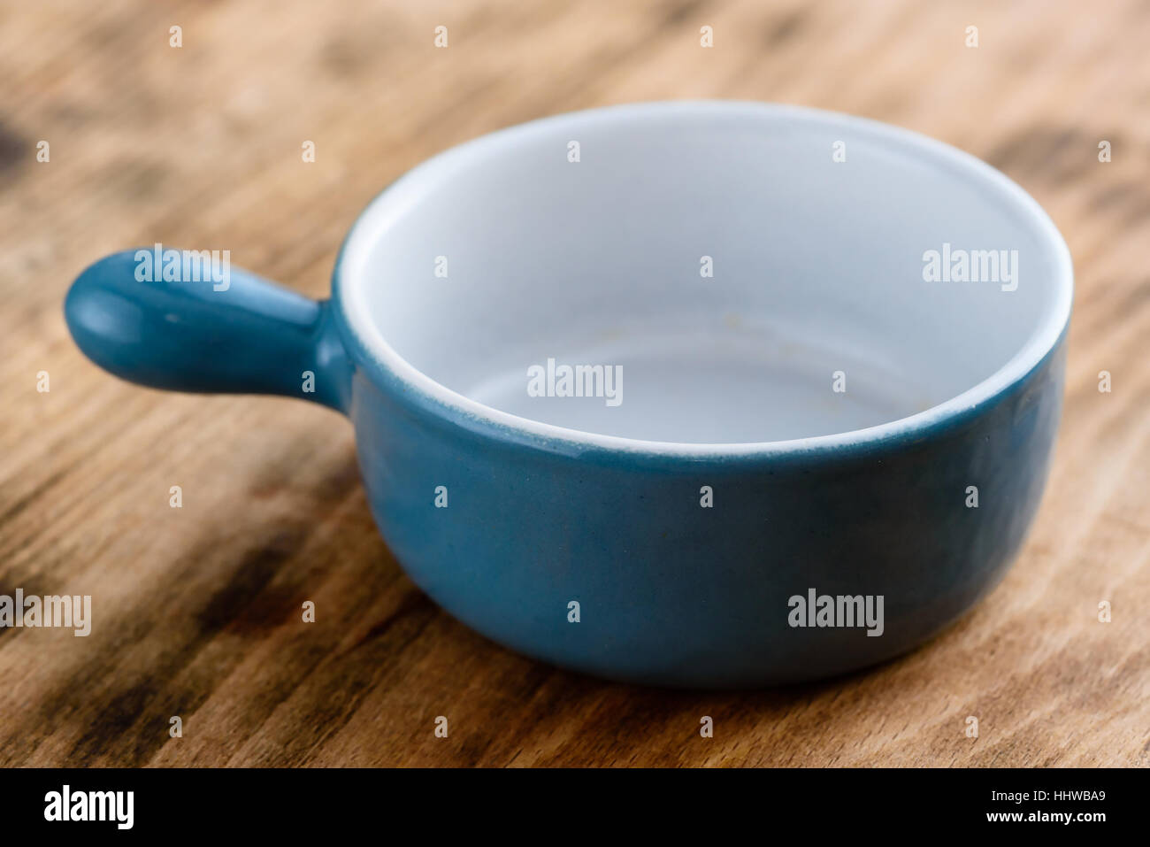 Small and blue enameled cast iron pot on wood. Stock Photo