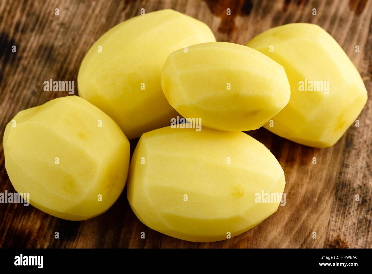 Moist and raw peeled potatoes on wooden board Stock Photo