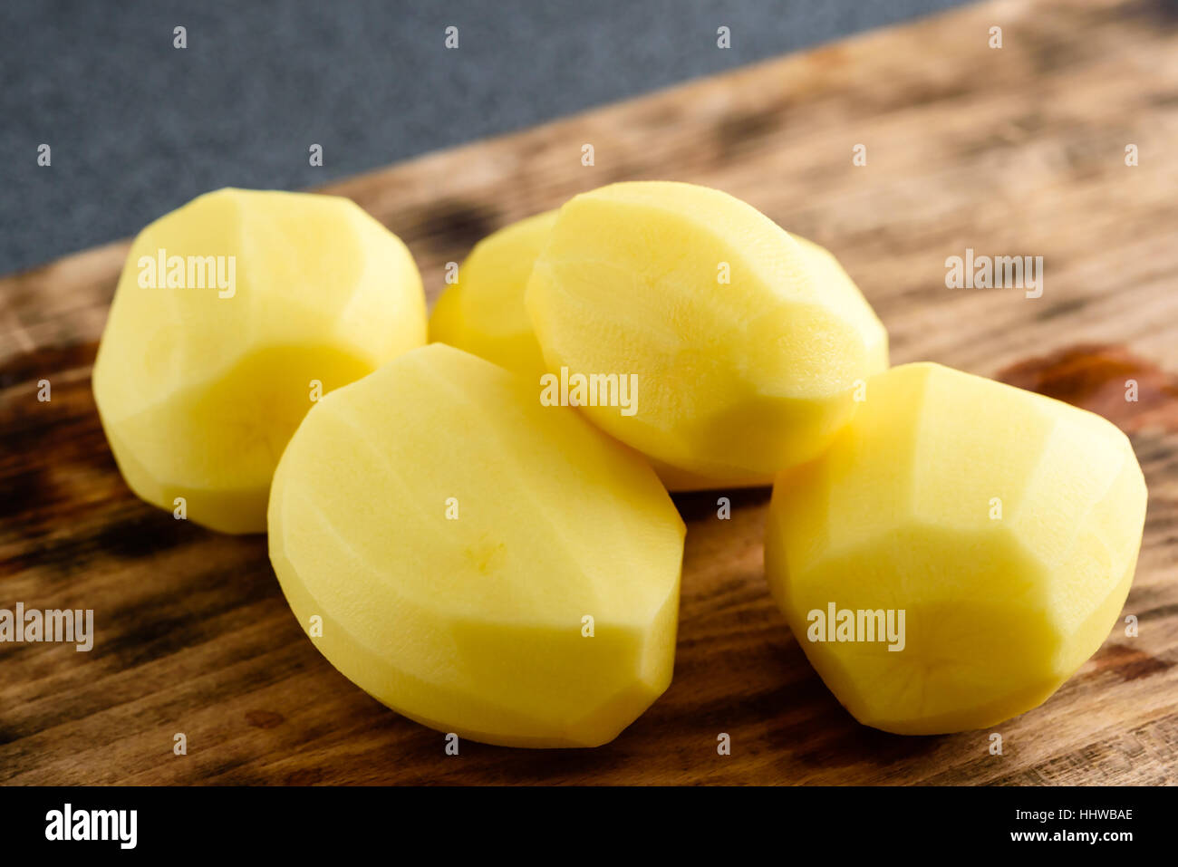 Moist and raw peeled potatoes on wooden board Stock Photo