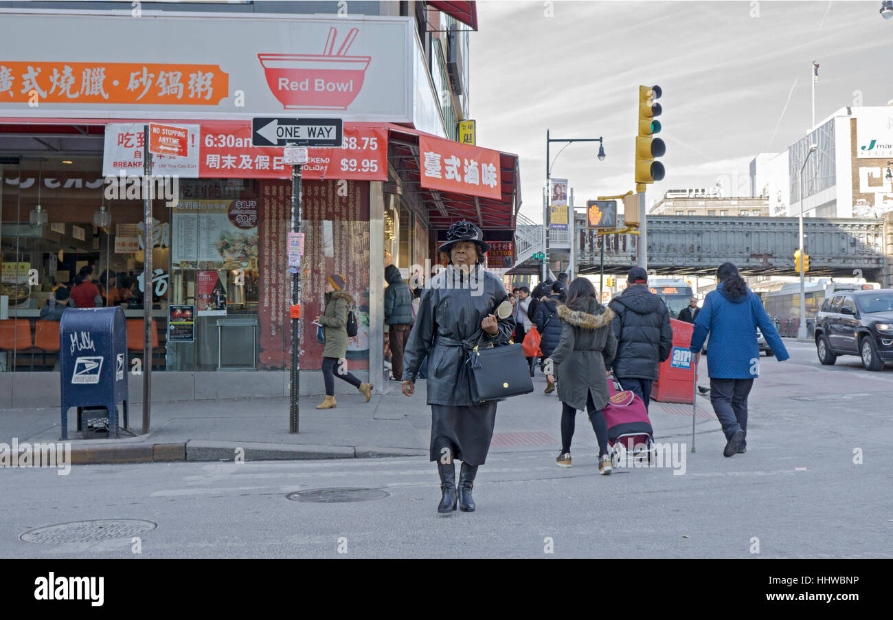 A stylish older African American woman dressed in black crosses a street in Chinatown, downtown Flushing, Queens, New York Stock Photo