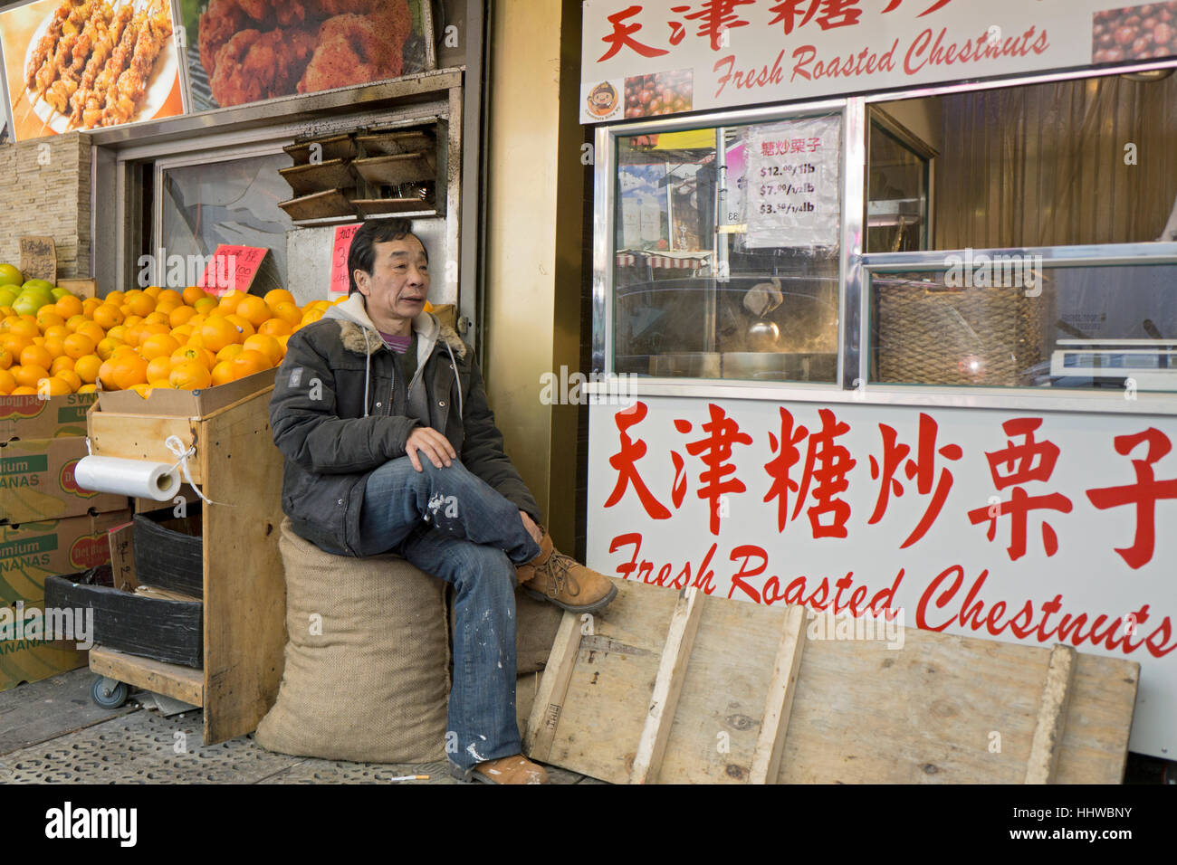 A Chinese American laborer takes a work break on a side Street in Chinatown, downtown Flushing, New York City Stock Photo