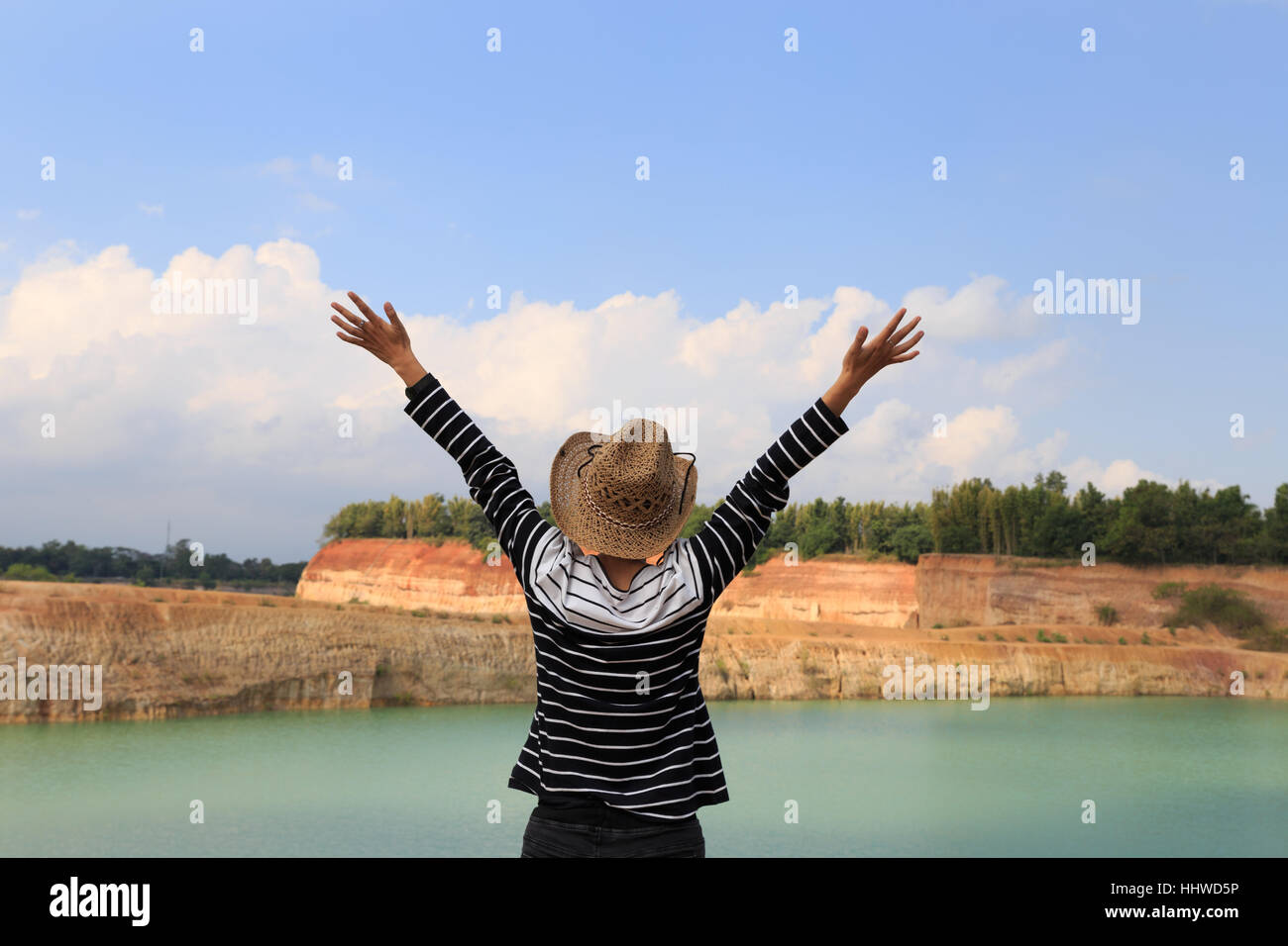 woman raise her hands up feeling happy and free at orange hill and green pond Stock Photo