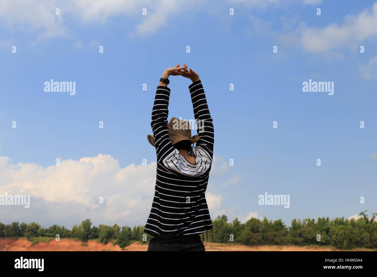 woman raise her hands up feeling happy and free at orange hill and green pond Stock Photo