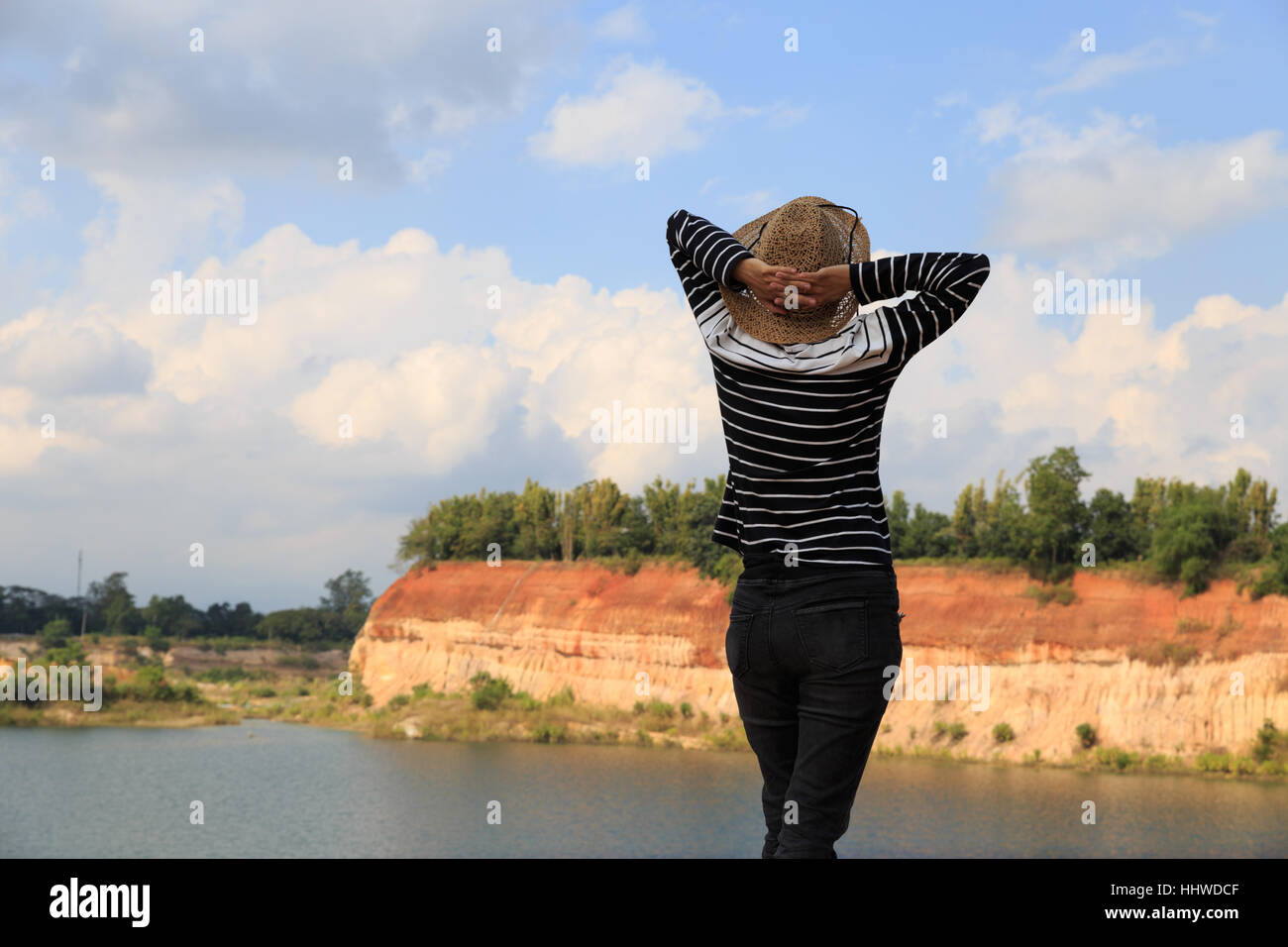 woman raise her hands feeling happy and free at orange hill and green pond Stock Photo