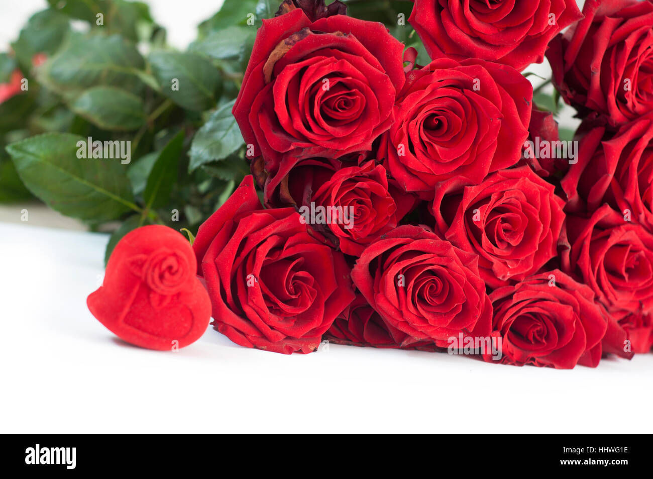 An heart shaped box with an engagement ring and roses on white isolated