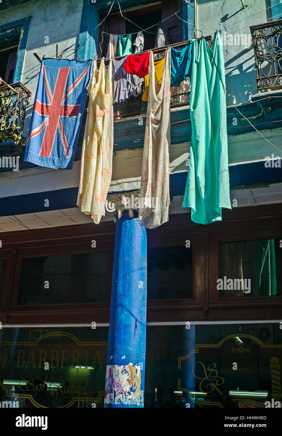 Clothes drying on line above central Havana shop bright blue pillar Stock Photo
