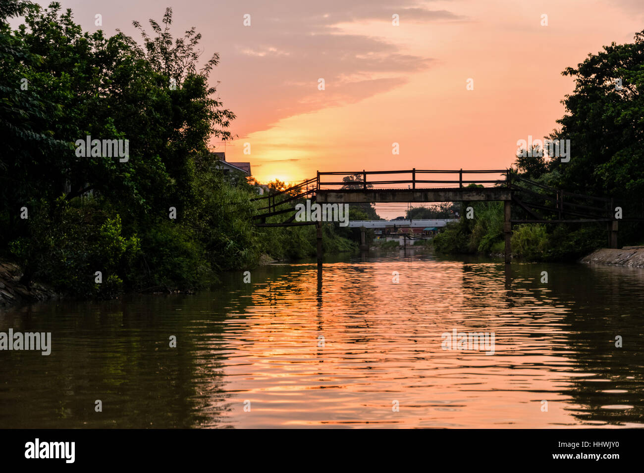 Landscape small canals, water is used as a thoroughfare rural and old wooden bridge for crossing the water during sunset in Phra Nakhon Si Ayutthaya Stock Photo