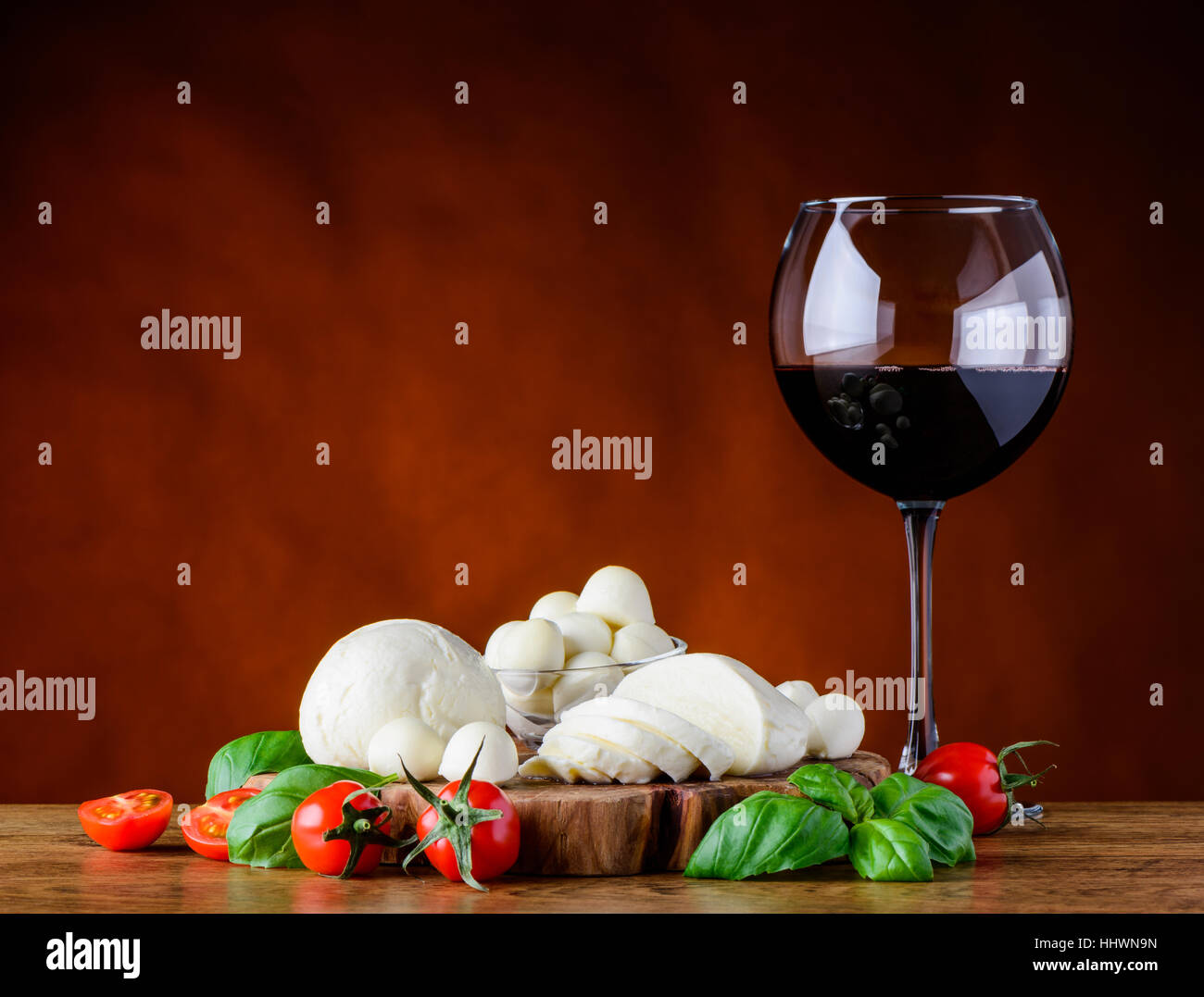 Wineglass of red wine with Juicy mozzarella cheese balls and tomato with basil Stock Photo
