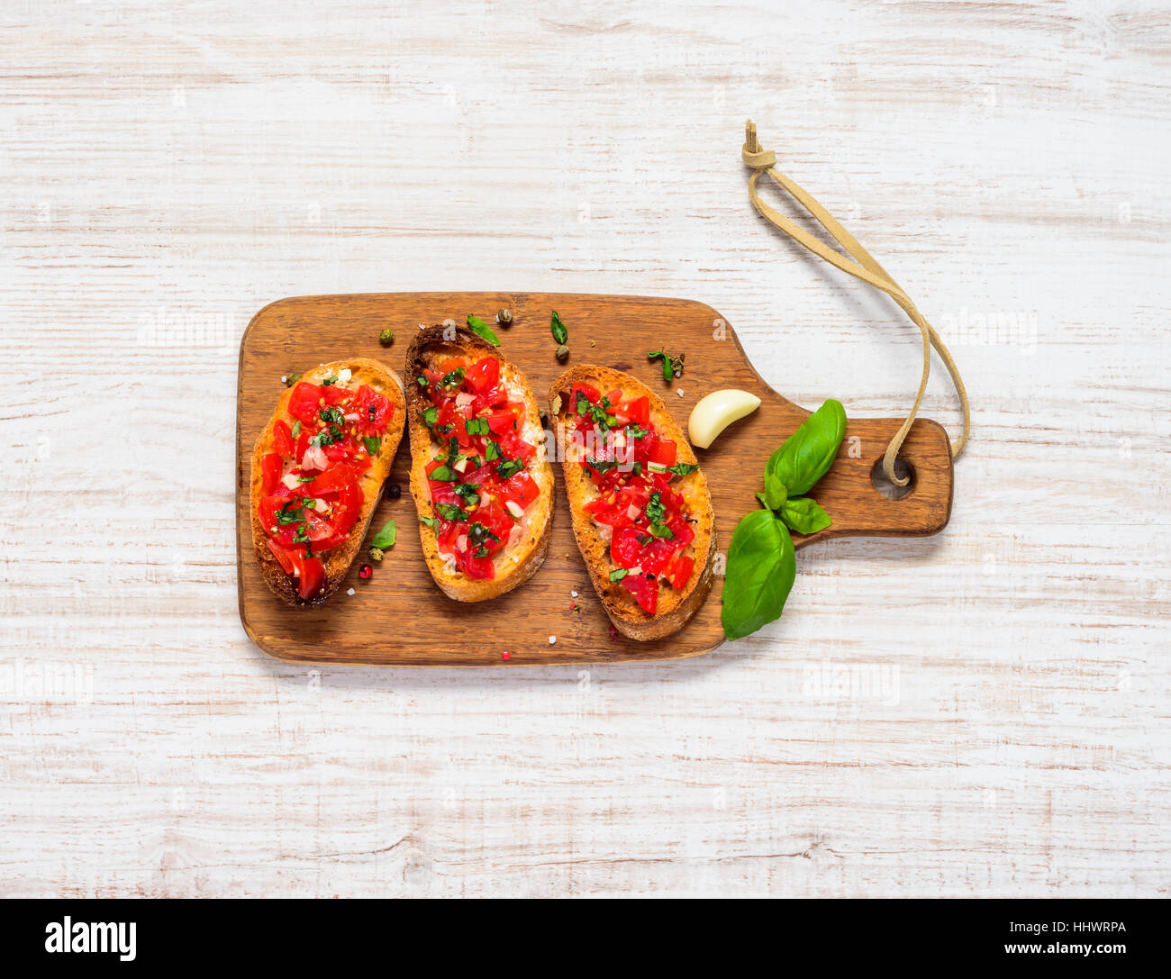 Antipasto Bruschetta with Grilled Bread, Tomato and Basil on Wooden Chopping Board Stock Photo