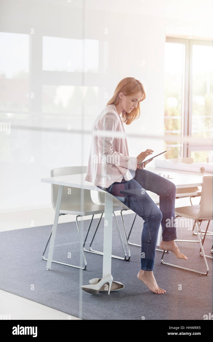 Barefoot businesswoman using digital tablet in conference room Stock Photo