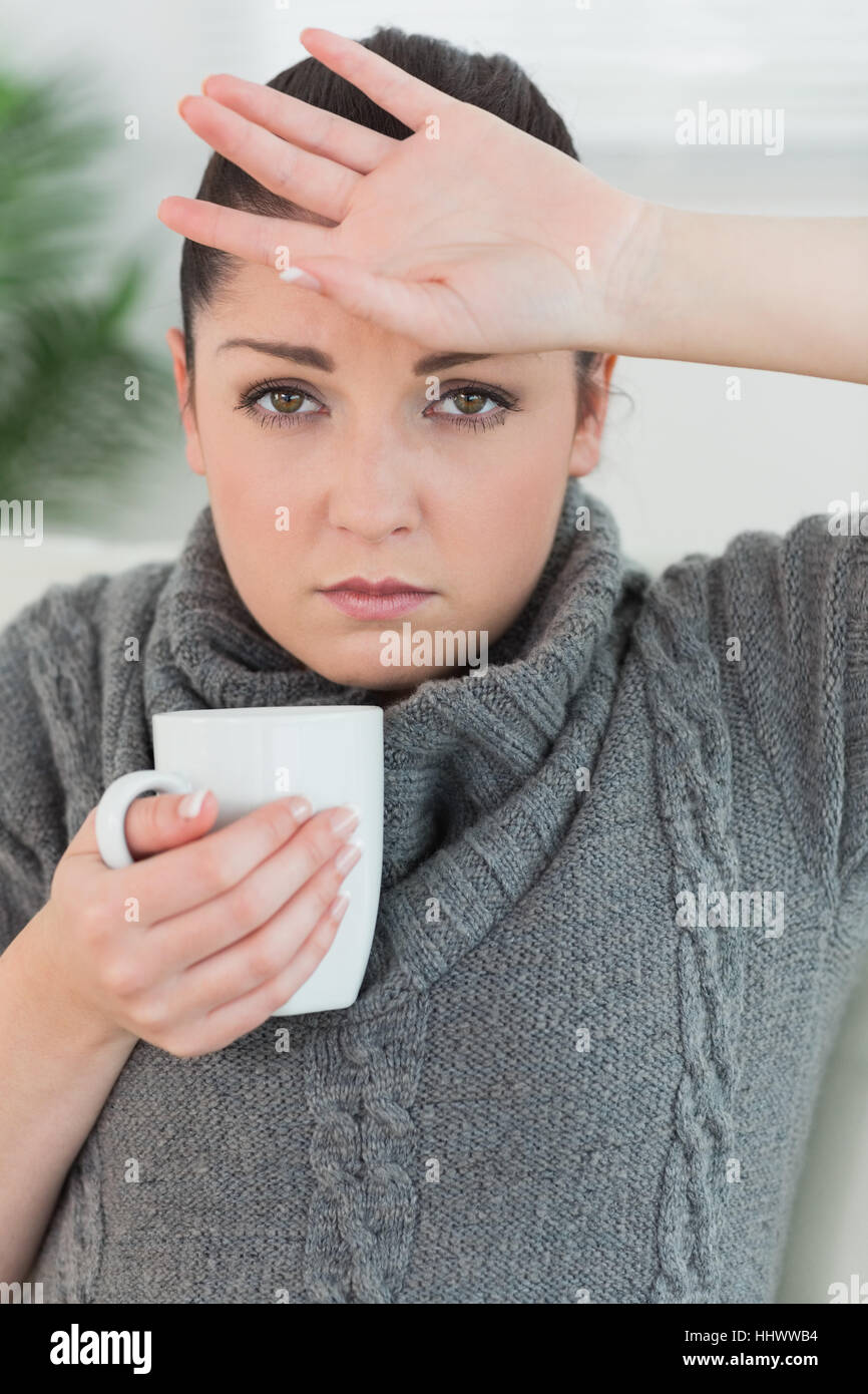 Young woman feeling ill while sitting on the couch in a living room and