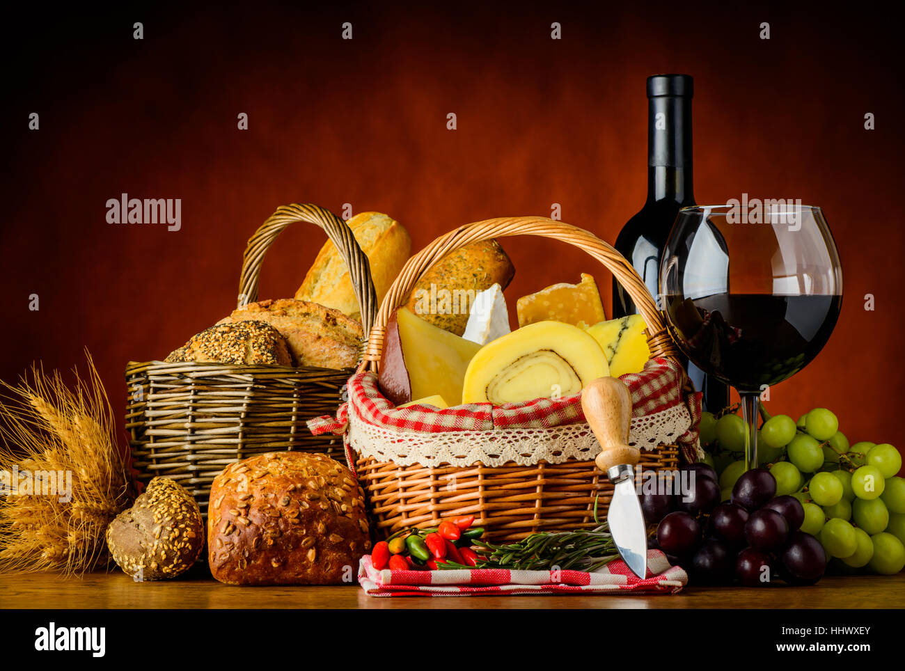Still life with Bottle and glass of red wine and basket with cheese and ...