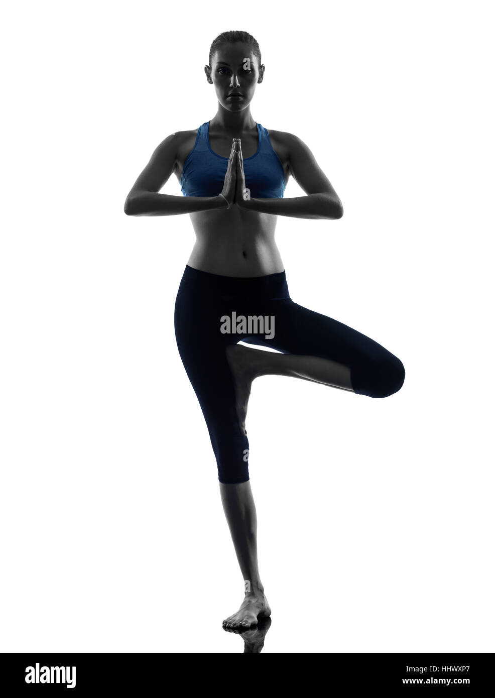 one caucasian woman exercising yoga tree pose in silhouette studio ...