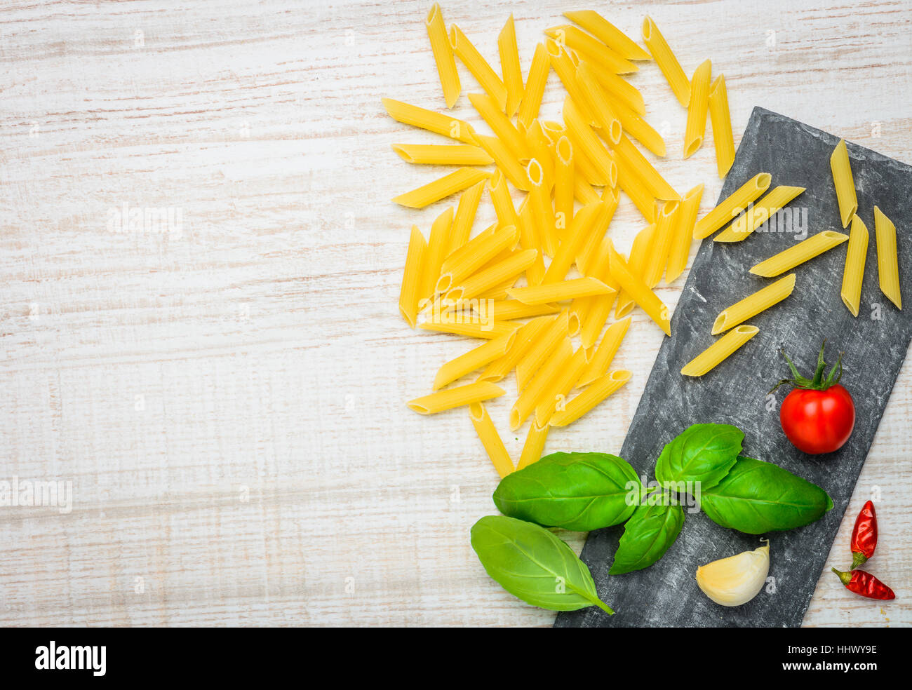 Italian cuisine, yellow Penne Doppia Rigatura and basil with tomato and copy space Stock Photo