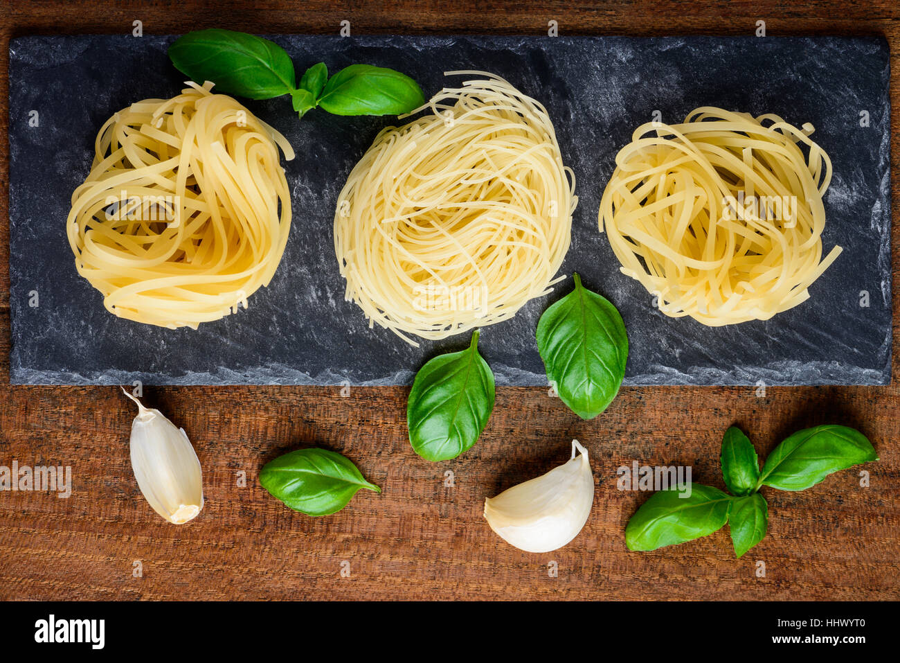Yellow Tagliolini with basil and garlic cooking ingredients. Italian or mediterranean cuisine food Stock Photo