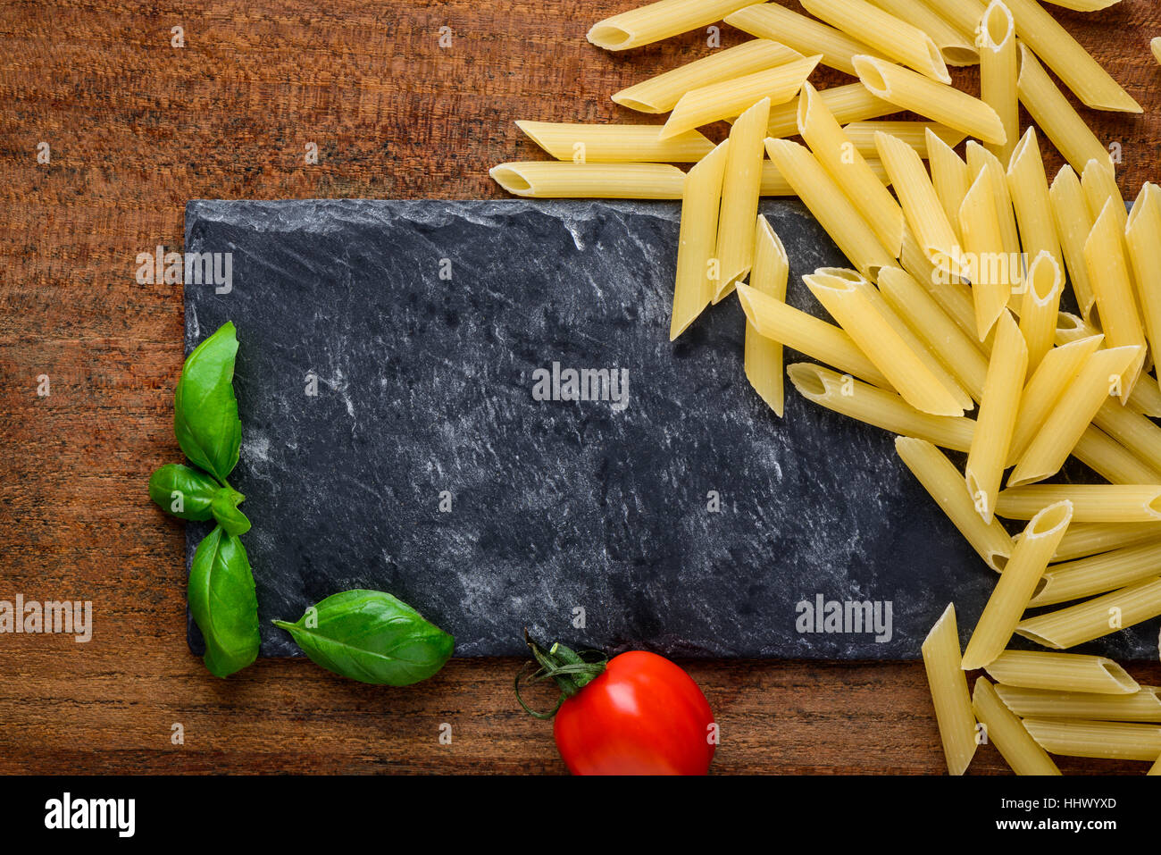 Yellow Penne Pasta and Copy space area with basil and tomato Stock Photo