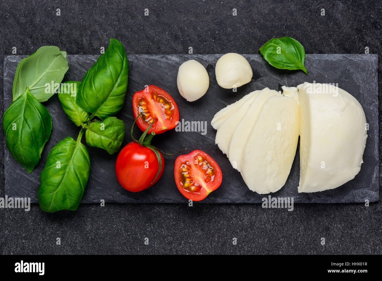 Green fresh leaves of basil with red tomato and Italian juicy mozzarella cheese Stock Photo