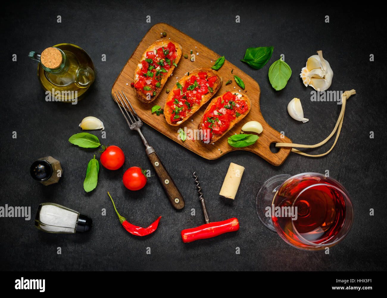 Italian Antipasto with Bruschetta, Tomato and Basil on Black Table with Rose Wine Stock Photo