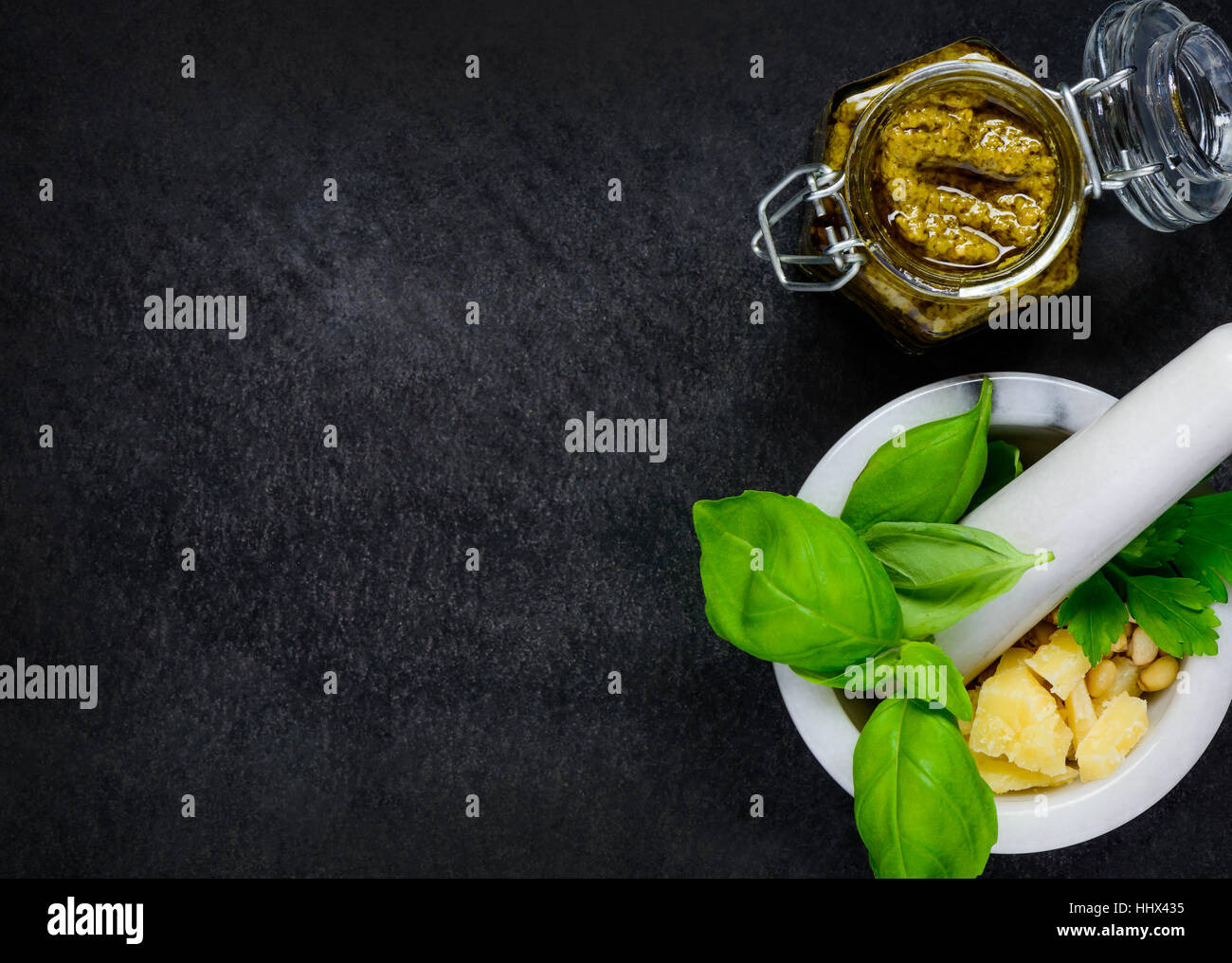 Copy Space Area of Pesto with Pestle and Mortar with Basil, Parmesan cheese and Pine Nuts in Top view Stock Photo