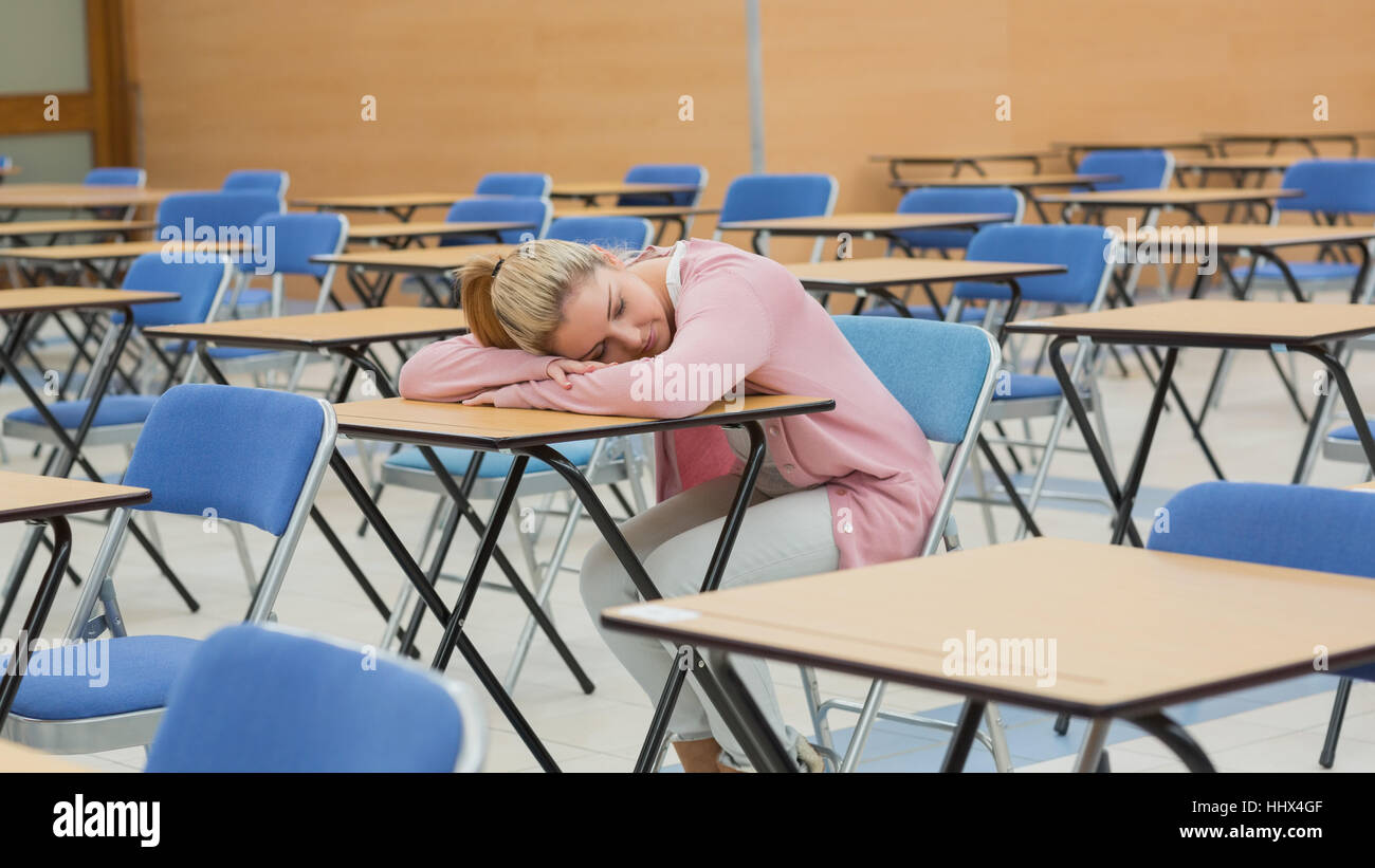 Woman leaning on desk napping in exam hall Stock Photo