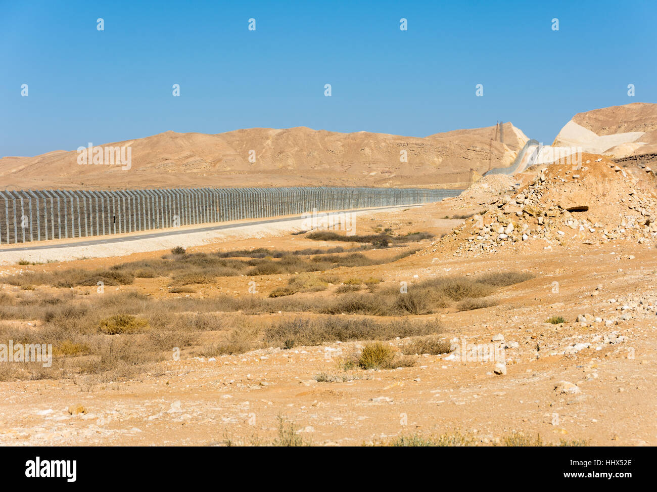 The new border fence between Israel (Negev Desert) and Egypt (Sinai Desert) with the patrol road protecting the border Stock Photo