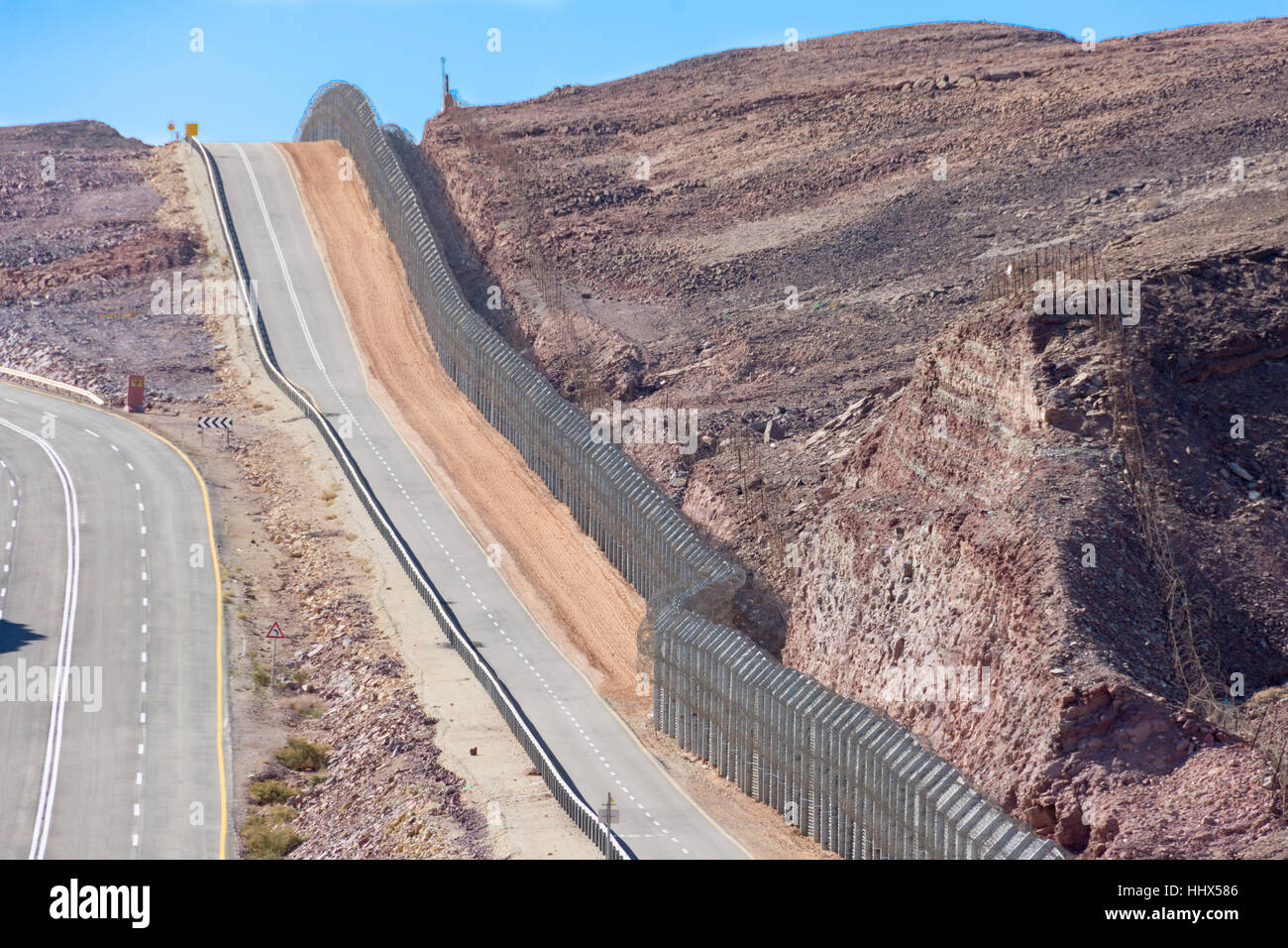 The new border fence between Israel (Negev Desert) and Egypt (Sinai Desert) with the patrol road protecting the border Stock Photo