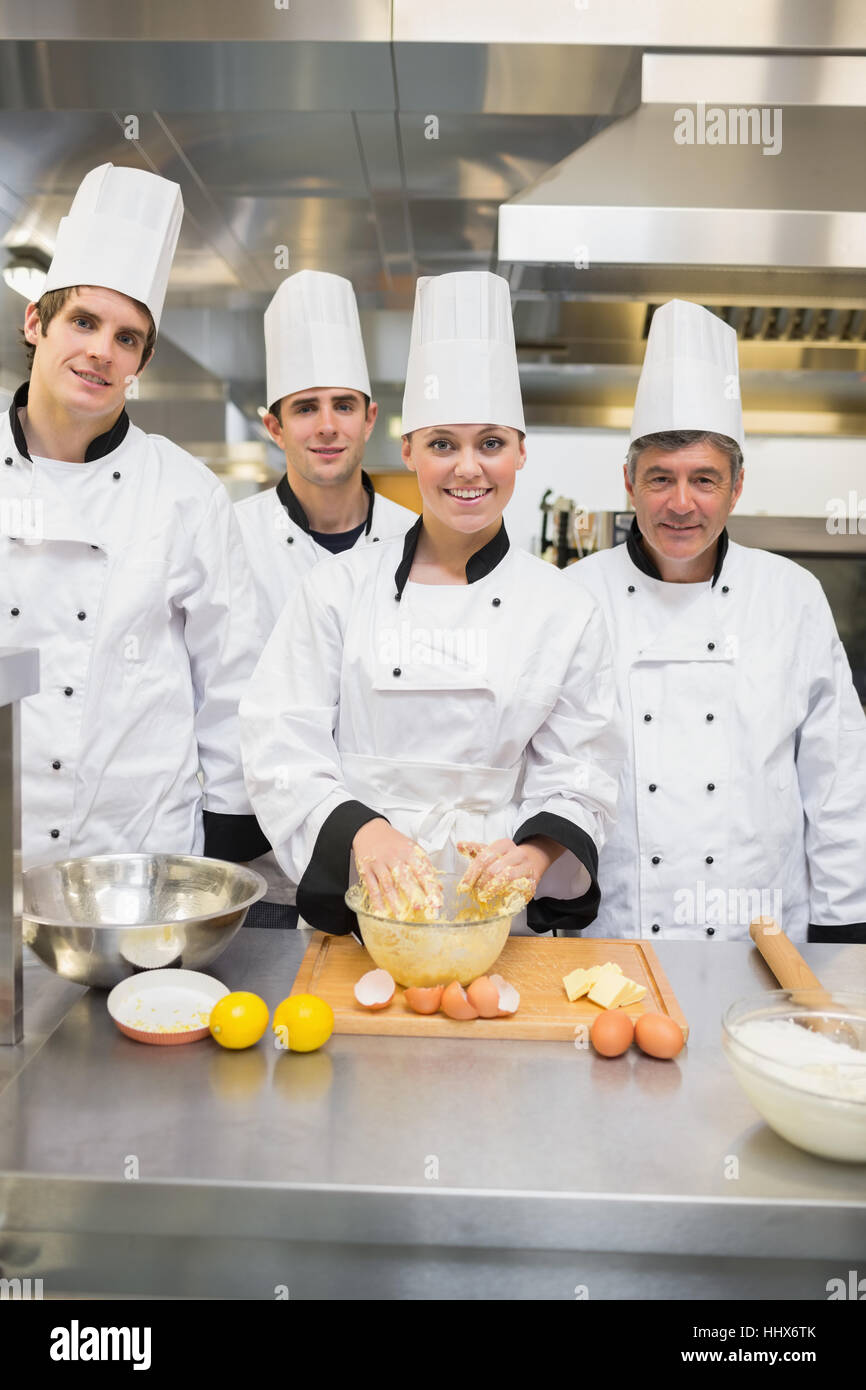 Smiling culinary students with pastry teacher in kitchen Stock Photo