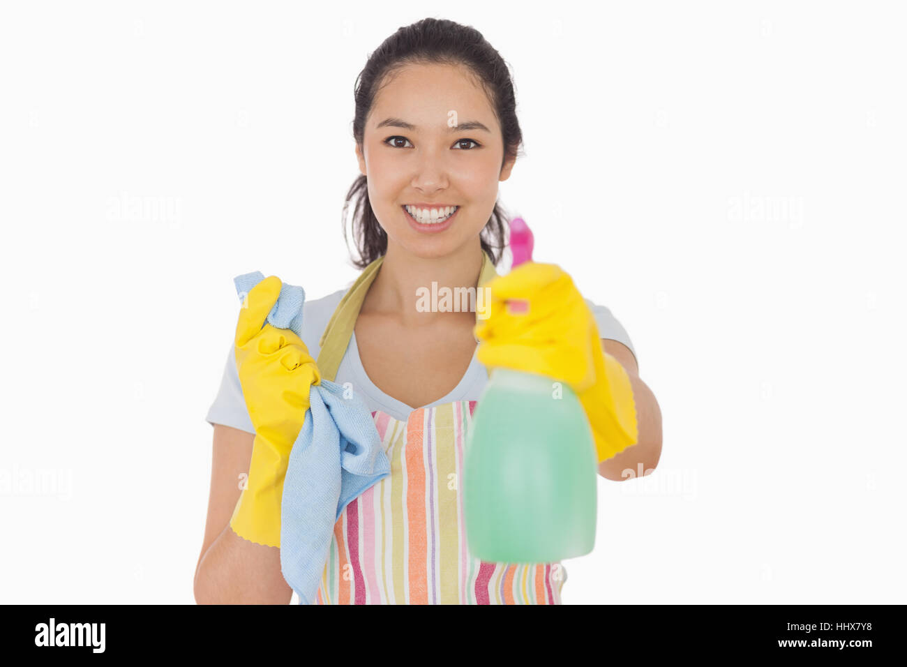 Cheerful woman holding up spray bottle in rubber gloves and apron Stock