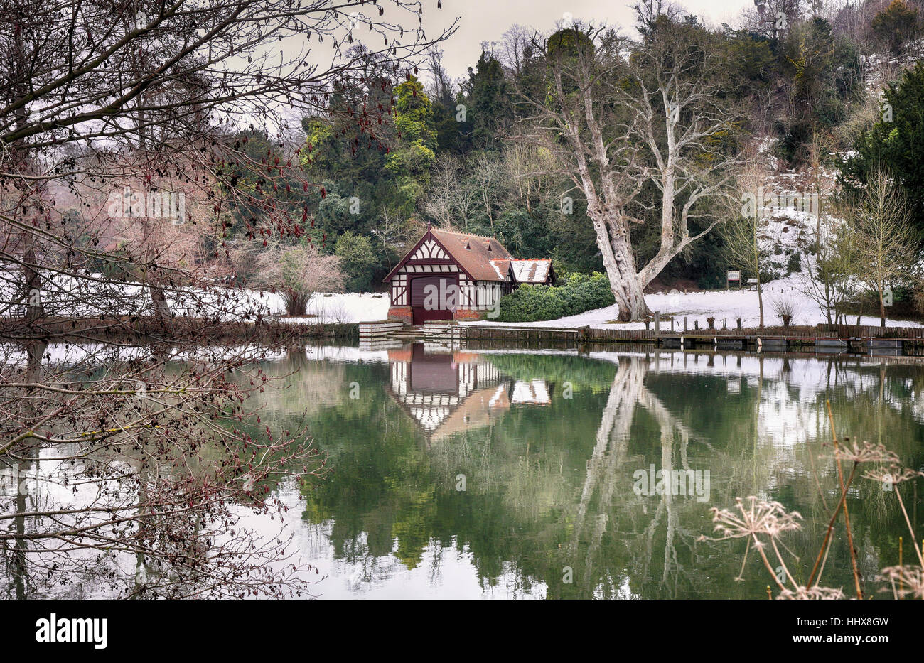 Winter on the River Thames in England with boathouse and snow covered riverbank Stock Photo