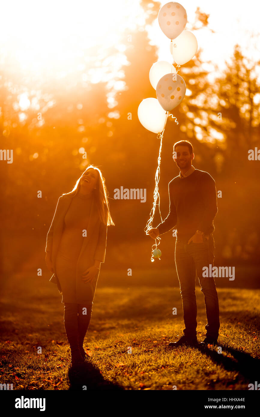 Young pregnant woman and man posing in autumn park with balloons in ...