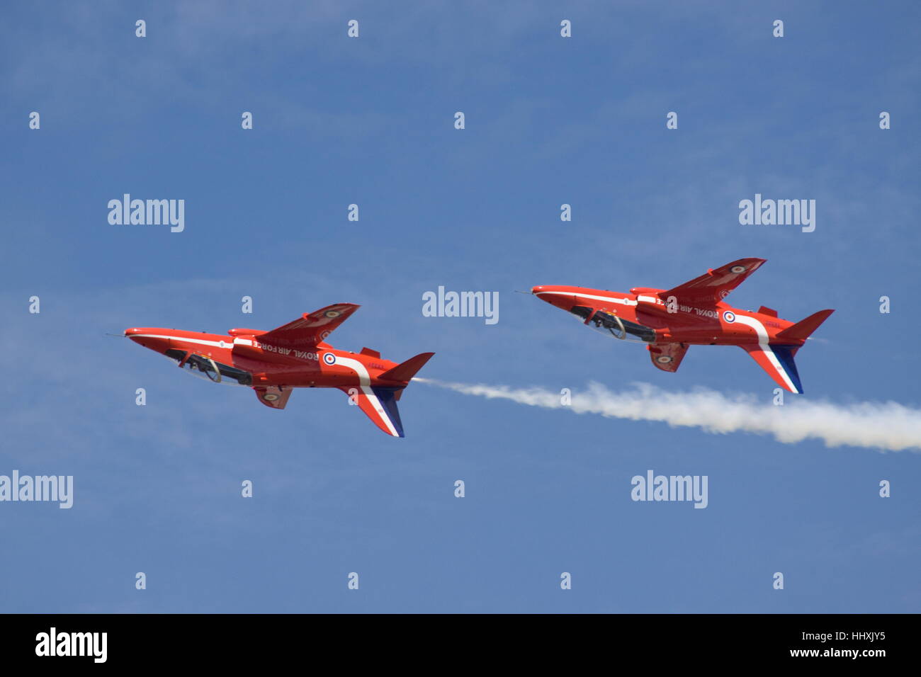 Two Red Arrows BAE Hawk T1A flying upside down against a blue sky. Stock Photo