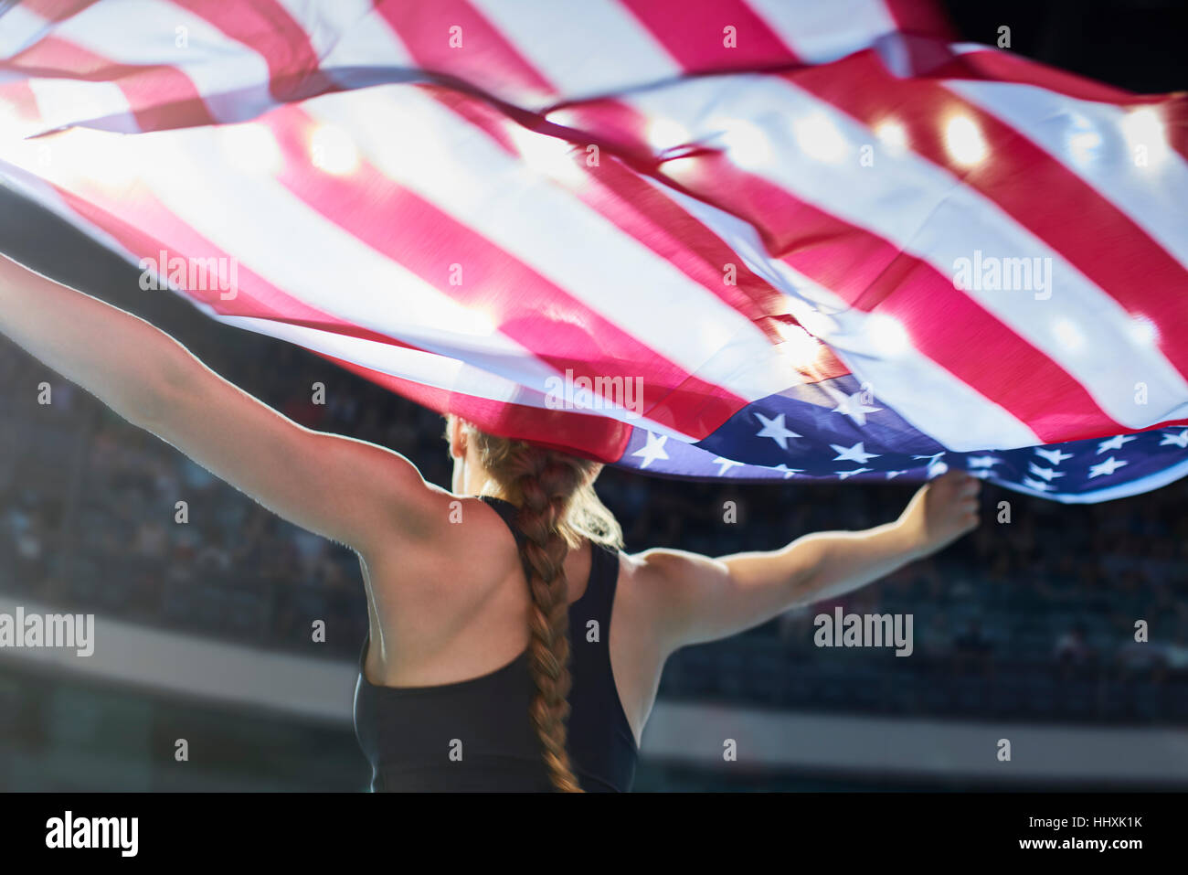 Female athlete running victory lap with American flag Stock Photo