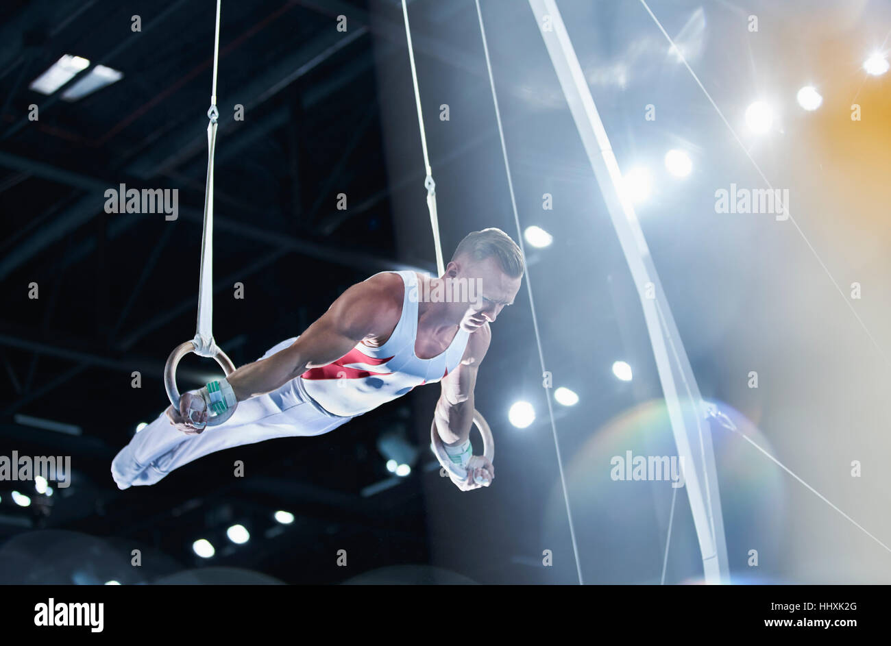 Male gymnast performing on gymnastics rings in arena Stock Photo Alamy