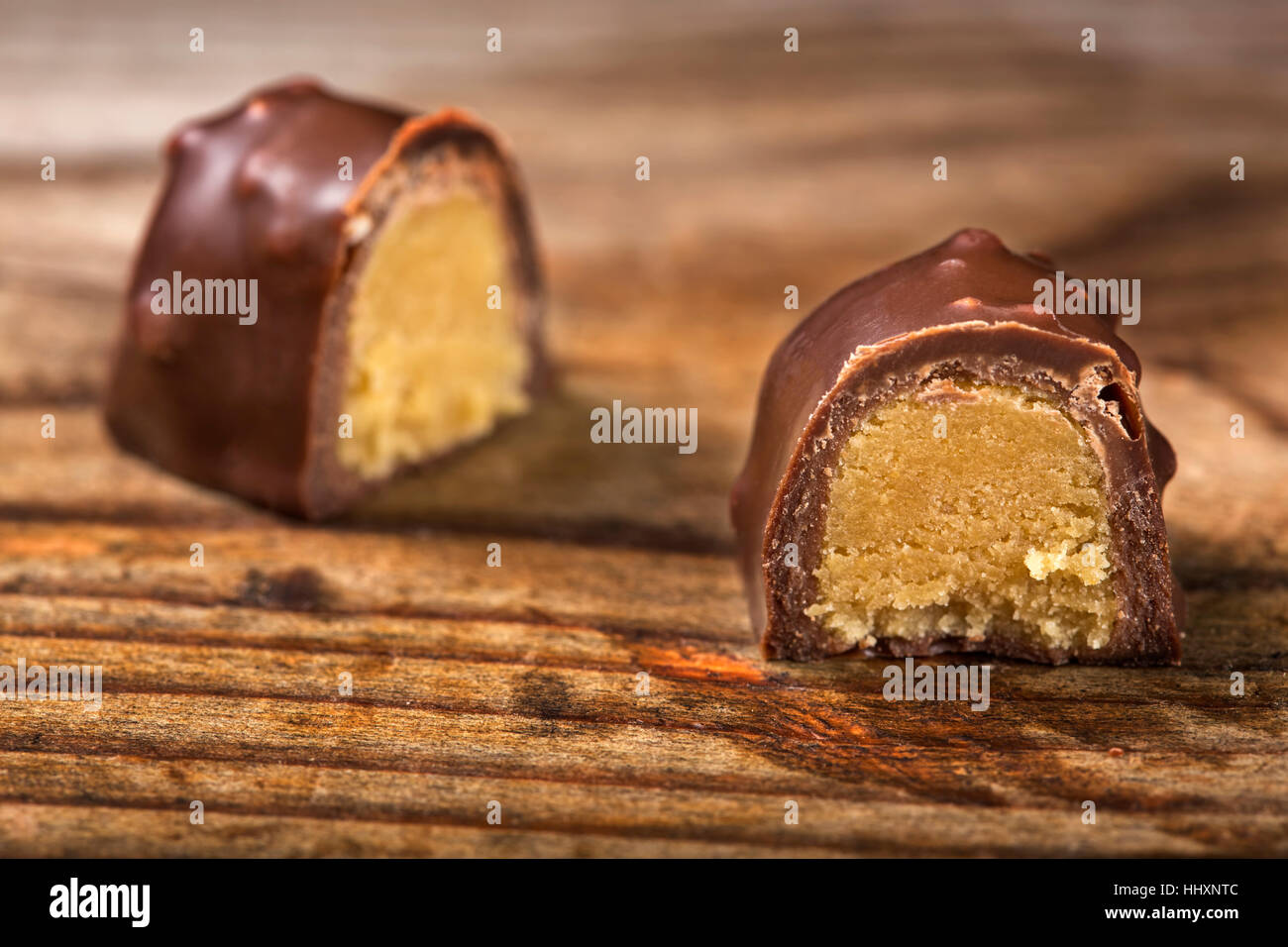 One chocolate candy cut in half over wooden background Stock Photo